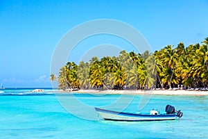 Summer vacation and tropical beach concept. Blue boat against sandy beach with palms and turquoise sea. Vacation island