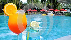 Summer vacation. Two glasses of tropical iced drinks on poolside with fun people