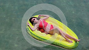 Summer vacation woman in bikini on inflatable avocado