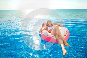 Summer Vacation. Woman in bikini on the inflatable donut mattress in the SPA swimming pool.