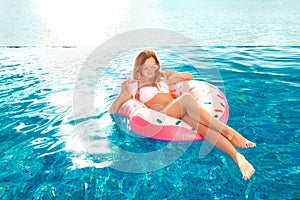 Summer Vacation. Woman in bikini on the inflatable donut mattress in the SPA swimming pool.