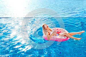 Summer Vacation. Woman in bikini on the inflatable donut mattress in the SPA swimming pool.