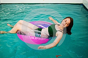 Summer vacation woman in bikini on inflatable donut mattress in swimming pool. girl relaxing sunbathing enjoying travel holidays a