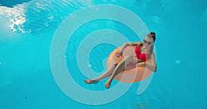 Summer Vacation Woman in bikini on inflatable mattress in swimming pool. Top view of girl relaxing sunbathing enjoying