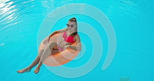 Summer Vacation Woman in bikini on inflatable mattress in swimming pool. Top view of girl relaxing sunbathing enjoying