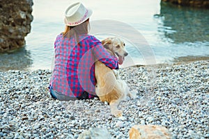 Summer vacation, woman with a dog on a walk on the beach