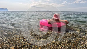 Summer vacation woman floats on an inflatable donut mattress, a water toy swim ring. Positive happy woman relaxing and