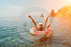 Summer vacation woman in hat floats on an inflatable donut mattress. Happy woman relaxing and enjoying family summer