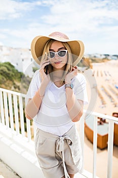 Summer vacation woman using cellphone texting sms message outside on balcony terrace . Europe Happy young girl relaxing in sun on