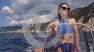 Summer vacation - young girl driving a motor boat on the sea. Slow motion