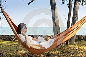 Summer vacations concept, Happy asian woman with white dress, sleeping rest and relaxing in hammock on tropical beach at sunshine