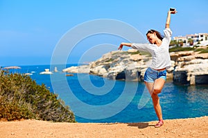 Summer vacations. Girl with hands up near the sea.