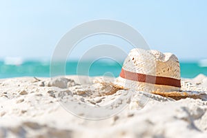 Summer Vacations. Hat of traveler on the sandy beach with blue sky background.