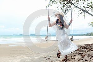 Summer Vacations. Lifestyle women relaxing and enjoying swing on the sand beach, fashion stunning women with white dress on the tr