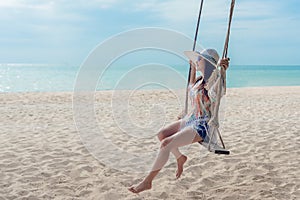 Summer Vacations. Lifestyle women relaxing and enjoying swing on the sand beach, fashion stunning women on the tropical island so