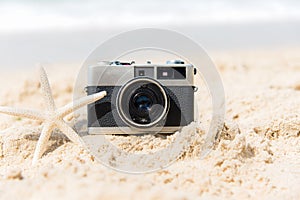 Summer Vacations. Vintage old camera of tourism on sandy beach with star fish.