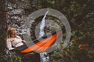 Summer vacations - woman chilling in hammock in forest travel outdoor tourist girl enjoying waterfall view in Norway