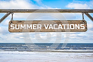 Summer vacations wooden sign against blue sky and sea with waves background