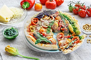 Summer vegetarian pizza with edible flowers and pine nuts