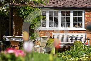 Summer view of a domestic home garden with flowers lawn and patio furniture in the background