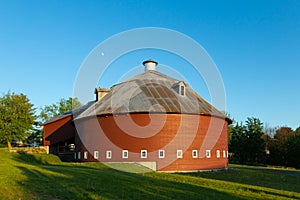 Summer view of early 20th century wooden circular red barn with gambrel roof photo