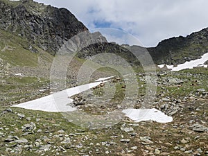 Summer view of rocky alpine landscape with mountain peak ridge Niederl saddle, snow spots meadow with grazing sheep