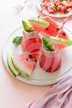 Summer watermelon smoothie decorated mint leaves and watermelon salad with feta cheese on pink background.