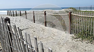 Summer waves on beach, California shoreline USA. Pacific ocean coast, picket fence on sea shore.