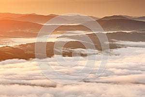 Summer weather phenomenon. Seasonal landscape with morning fog in valley. Clouds drenched valley below the level of the mountains.