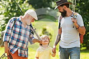 Summer weekend. Happy grandfather, father and grandson with fishing rods. Anglers. Men day. Fishing.