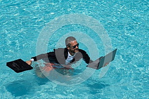 Summer weekend and remote freelance work. Crazy comic business. Funny businessman in suit with laptop in summer swimming