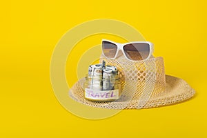 Summer weekend travel vacation concept. Beach accessories, straw hat, white sunglasses and save money glass jar with dollars