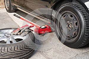 Summer wheel lying near car on winter tires