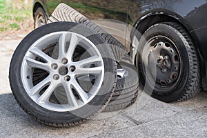 Summer wheels lying near car on winter tires