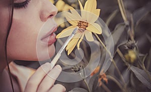 Summer woman face. Close up portrait of young attractive woman painting yellow flowers with brush. Flowers blossom and