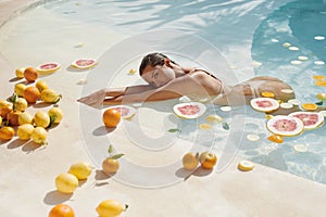 Summer Woman In Pool With Tropical Fruit Posing. Beautiful Model In Bikini At SPA.