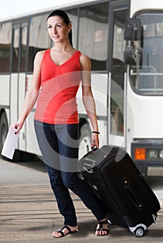 Summer woman with suitcase and travel ticket walking at the bus station