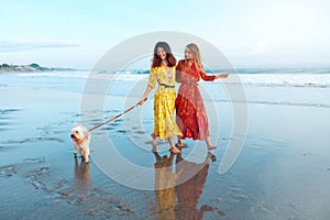 Summer. Women With Dog On Beach. Fashion Girls In Maxi Bohemian Clothing Walking With Pet On Dog-Friendly Coast