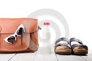 summer women set with leather bag, sandals, sunglasses and bottle of water isolated on white