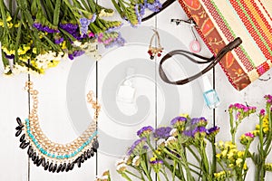 summer women set with straw bag, colorful flowers, cosmetics makeup, bijou and essentials on white wooden background