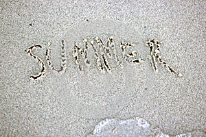 Summer word written on sand. Beach sand background texture