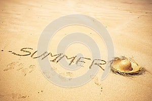 Summer word written on the sand at the beach in tropical scenic place for holiday vacation people concept - tourist hat for