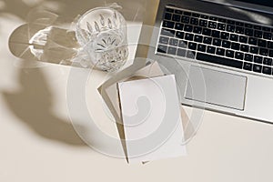Summer workspace composition with open laptop. Greeting card, invitation mockup. Glass of water, fresh drink in sunlight