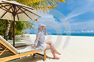 Summer young woman enjoying beach vacation in white dress, hat. Summer beach scene, hot weather, freedom concept