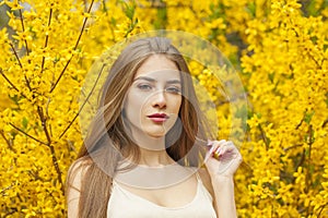 Summer young woman with natural makeup and healthy long brown hair in blossom park outdoors. Natural female beauty portrait