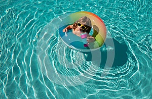 Summertime child boy in swiming pool on inflatable rubber circle ring. Summer kids weekend or vacation.