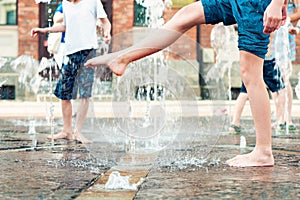 Summertime enjoyment. Kids legs in fountain