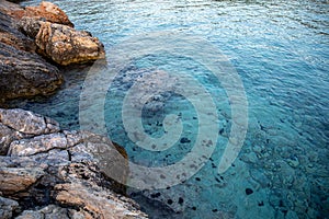Summertime evening crystal clear water with sea urchins on the rocks near the Aponissos beach, Agistri island, Saronic