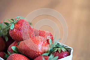 Summertime: Fresh red strawberries in a cup, wooden table