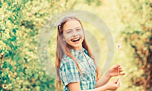 Summertime fun. Folklore beliefs about dandelion. Girl rustic style making wish and blowing dandelion nature background